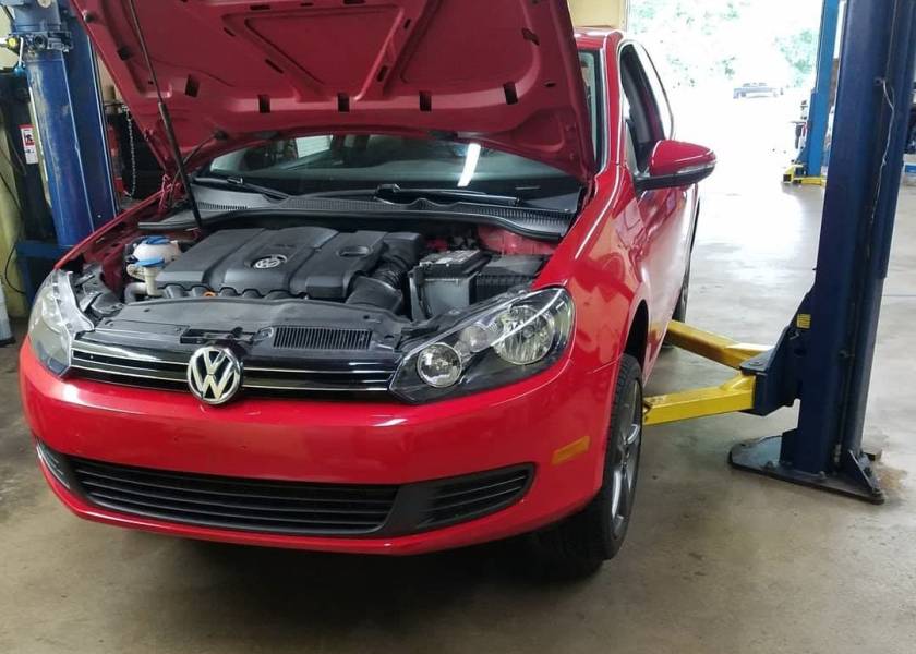 Car on a lift with the hood open at New Level Auto Service in Rockville, MD