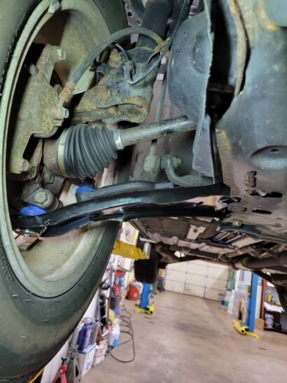 New black front lower control arm installed next to the CV axle on a car on the lift at New Level Auto Service in Rockville, MD