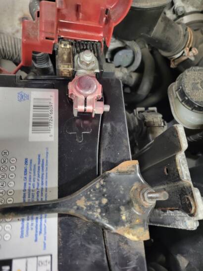Close-up of the battery terminals connected, with the red cover on the positive terminal, after a battery replacement