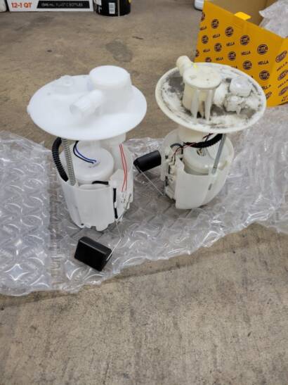 New fuel pump module on the left next to the old, dirty fuel pump module on the right, on bubble wrap on the shop floor at New Level Auto Service in Rockville, MD