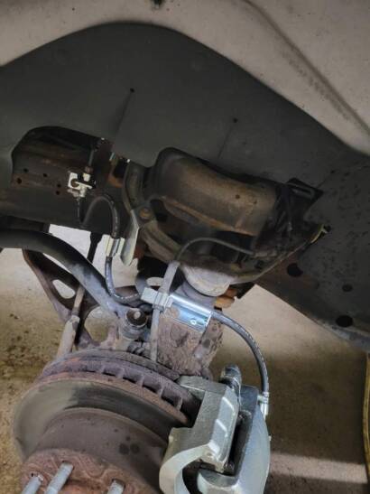 New silver brake caliper installed on a van's brake rotor, seen inside the wheel well at New Level Auto Service in Rockville, MD