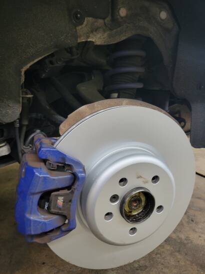 Close-up of a new brake rotor and blue brake caliper on an SUV at New Level Auto Service in Rockville, MD
