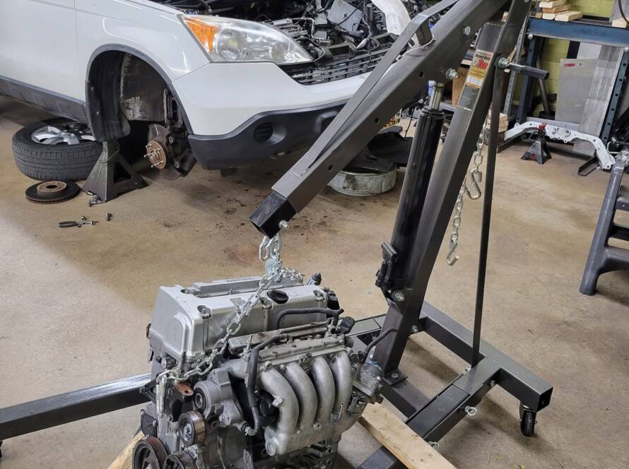 Car engine lifted out with a hoist during engine repair in Rockville, MD