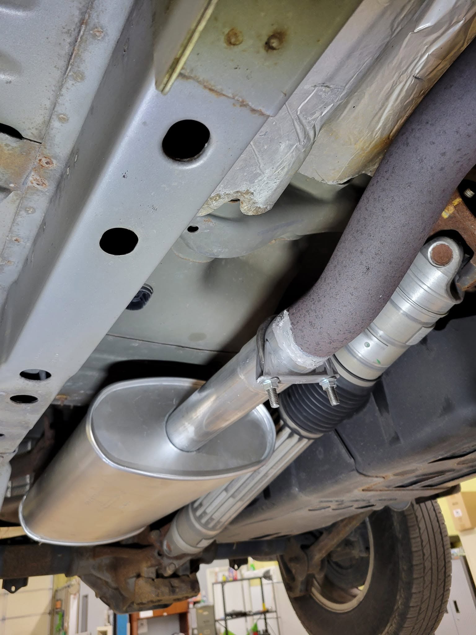 Exhaust system and muffler under a lifted car during repair in Rockville, MD